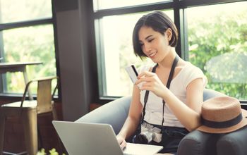 Woman holding credit card at coffe shop (Photo via torwai / iStock / Getty Images Plus)