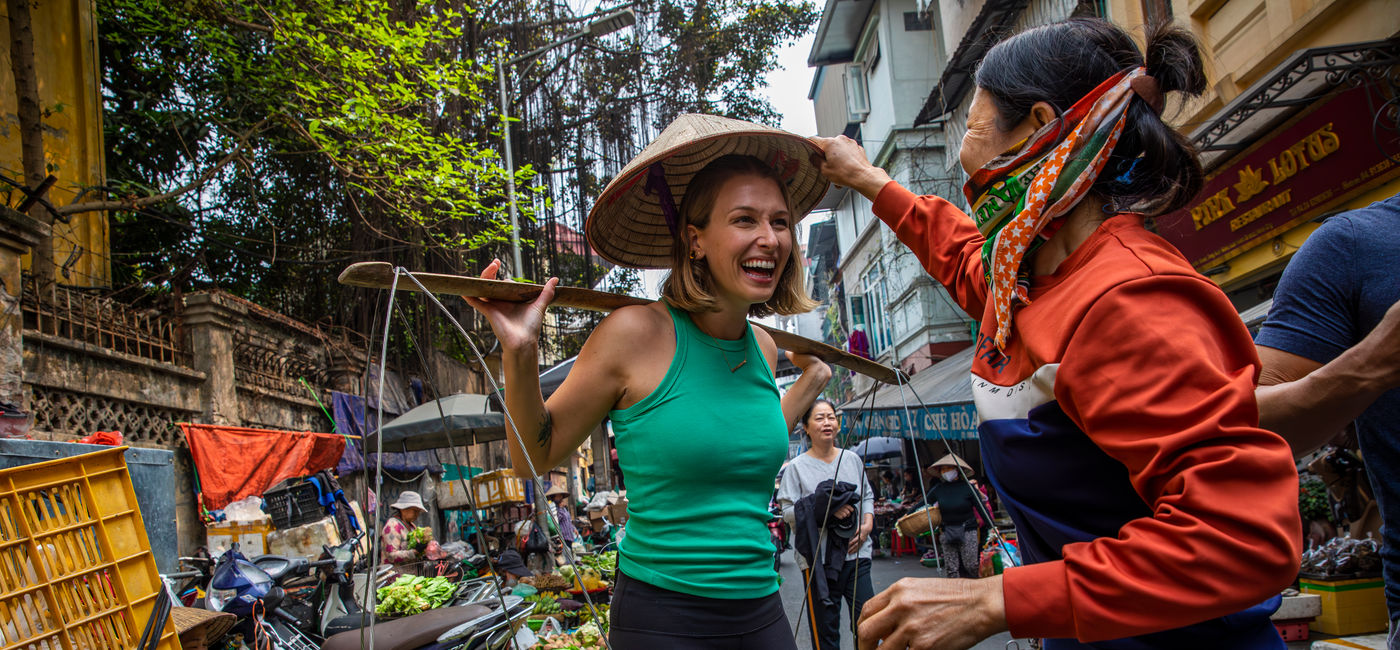 Image: A solo traveler experiences life as a seller in a food market in Hanoi, Vietnam. (Photo Credit: G Adventures)