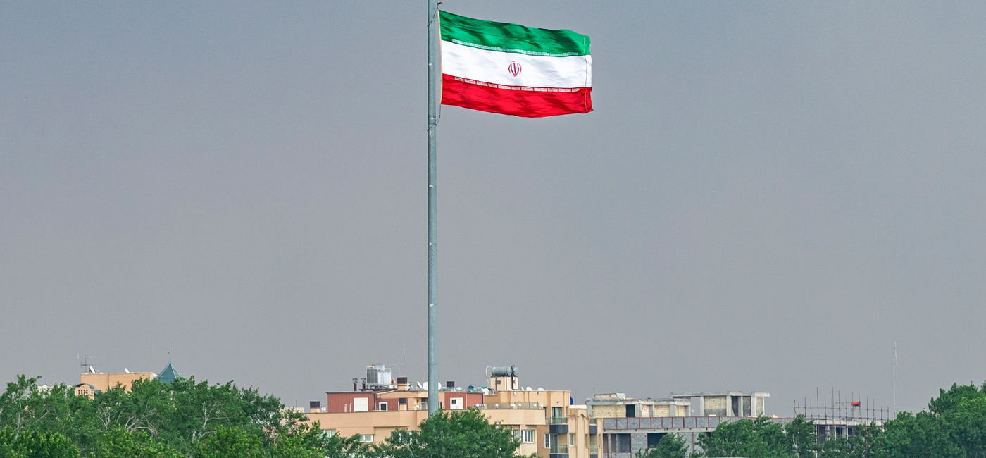 Image: Iranian flag from Khaju Bridge over the Zayandeh River. (Photo Credit: Alexeiy / Adobe Stock)