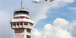 Air traffic control tower with an airplane taking off in the foreground.