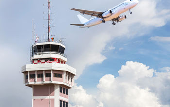 Air traffic control tower with an airplane taking off in the foreground.