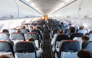Passengers seated inside of a commercial airplane cabin. 