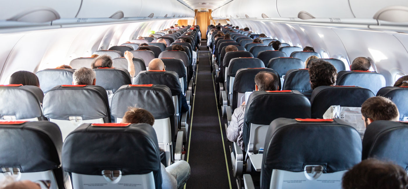 Image: Passengers seated inside of a commercial airplane cabin.  (Photo Credit: Adobe Stock/kasto)
