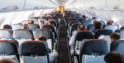 Passengers seated inside of a commercial airplane cabin.