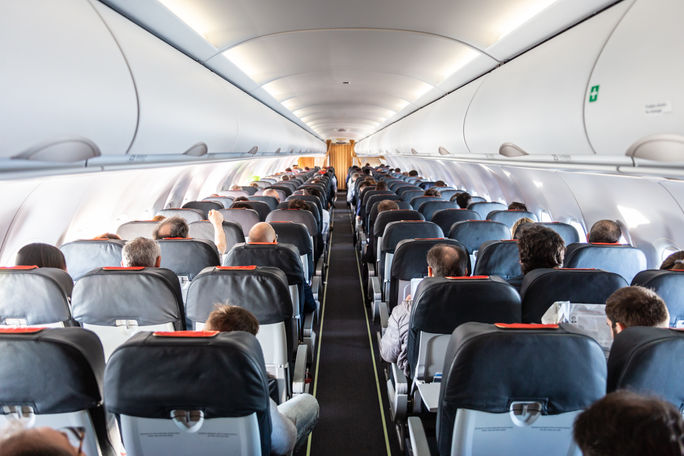 Passengers seated inside of a commercial airplane cabin. 