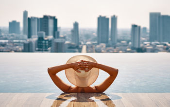 Woman enjoying a pool while overlooking a cityscape.