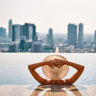Woman enjoying a pool while overlooking a cityscape.
