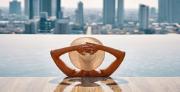 Woman enjoying a pool while overlooking a cityscape.