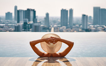 Woman enjoying a pool while overlooking a cityscape.