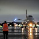 Ground crew member guides passenger plane.