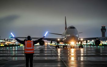 Ground crew member guides passenger plane.