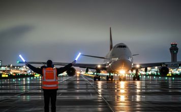 Ground crew member guides passenger plane.