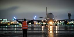 Ground crew member guides passenger plane.