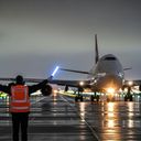 Ground crew member guides passenger plane.