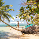 Woman walking on palm tree on beach