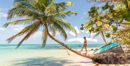 Woman walking on palm tree on beach