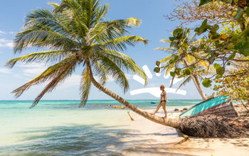 Woman walking on palm tree on beach