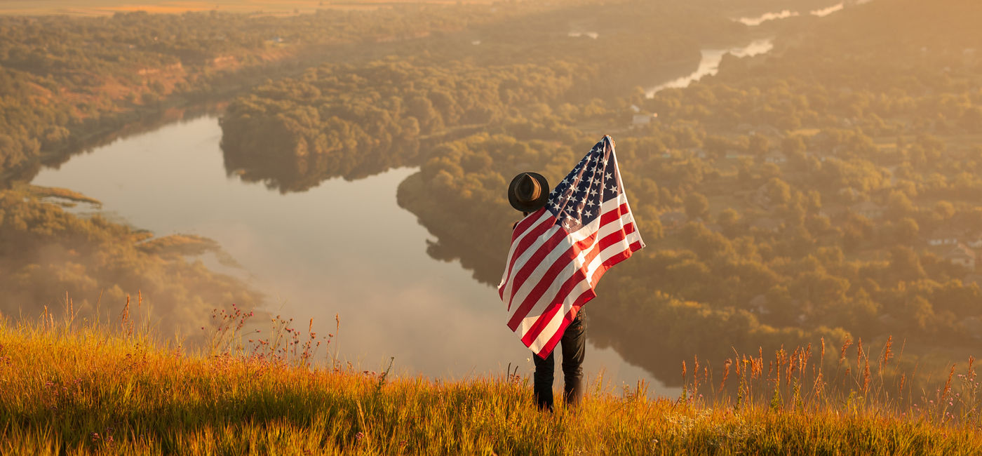 Image: Traveler with USA flag. (Photo Credit: kegfire / Adobe Stock)