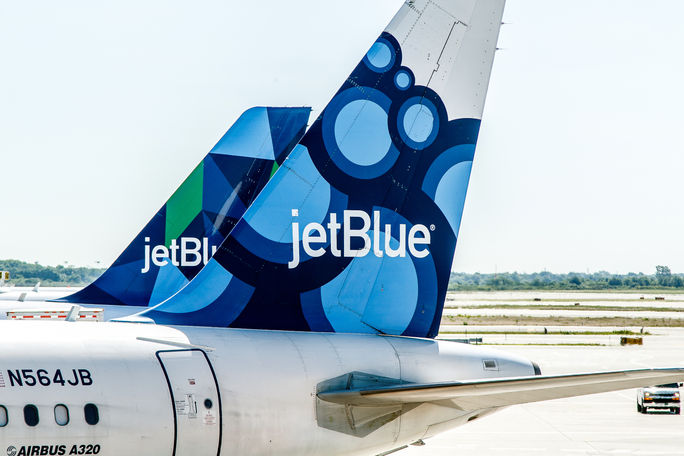 Two JetBlue airplanes parked. Two JetBlue airplanes parked.
