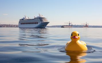 Rubber duck on the water with a cruise ship.