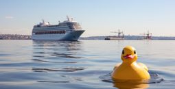 Rubber duck on the water with a cruise ship.