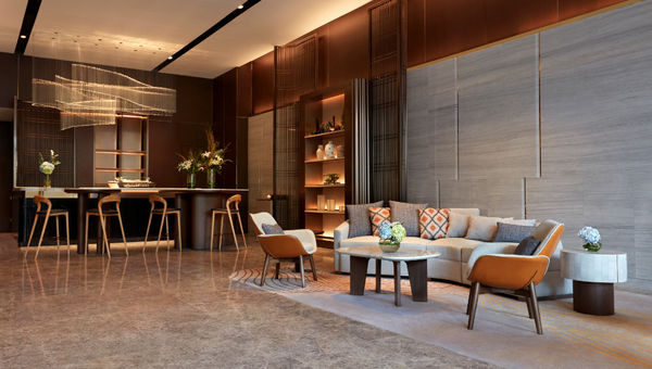 The lobby at Momentus Hotel Alexandra is a spacious and inviting space with high ceilings, comforting brown tones, and a stunning feature wall.