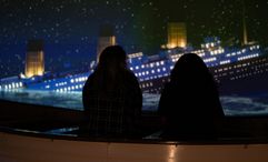 Visitors sit in a lifeboat replica, surrounded by immersive visuals and sound, simulating the panic and heartbreak as the Titanic sinks into darkness.