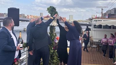 Champagne is poured over the ship's bell during the Trafalgar Verity's christening. Ship godmother Cassie Estrella-Roca is on the right.