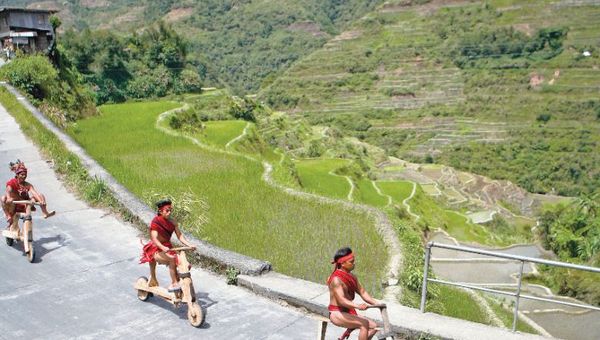 Riding on hand-carved wooden scooters through Banaue.