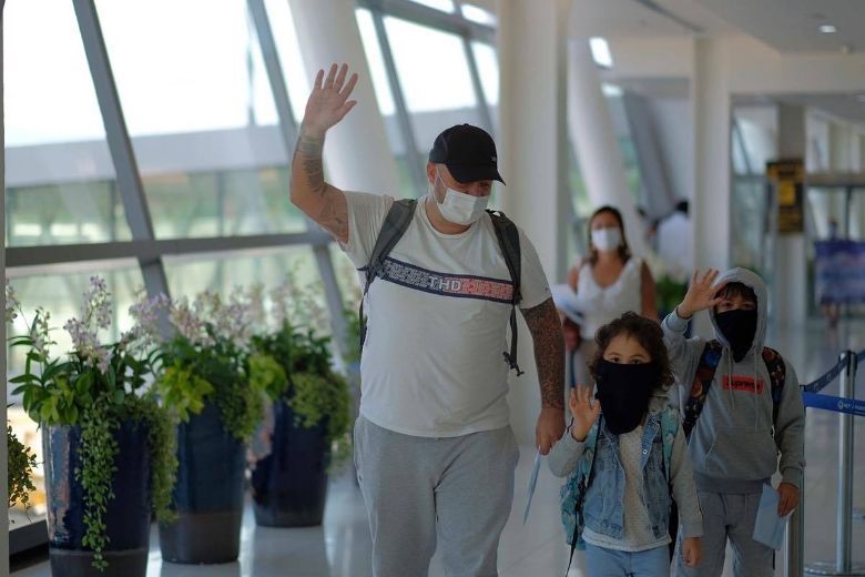 The first few tourists arriving at the airport give a wave as Phuket reopens to international tourism on 1 July.