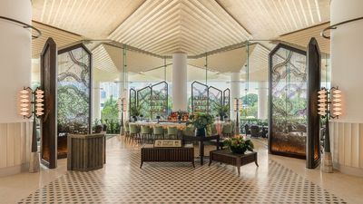 The Dusit Thani Bangkok’s lobby blends modern elegance with Thai heritage, featuring spacious design, luxurious furnishings, natural light, and panoramic views of Lumpini Park.