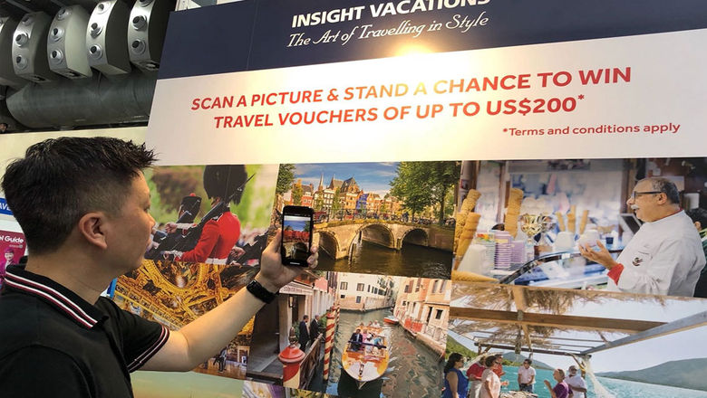 A customer scans the photos on display at Insight Vacations’ booth, after downloading the branded IV40 app from the Apple or Google Play app stores, to win instant prizes.