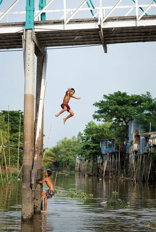 Boys take turns jumping off a bridge in Chau Doc, Vietnam.