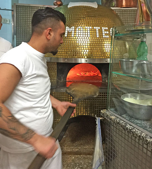 A pizzaiolo tends the oven at Di Matteo. A pizzaiolo tends the oven at Di Matteo.