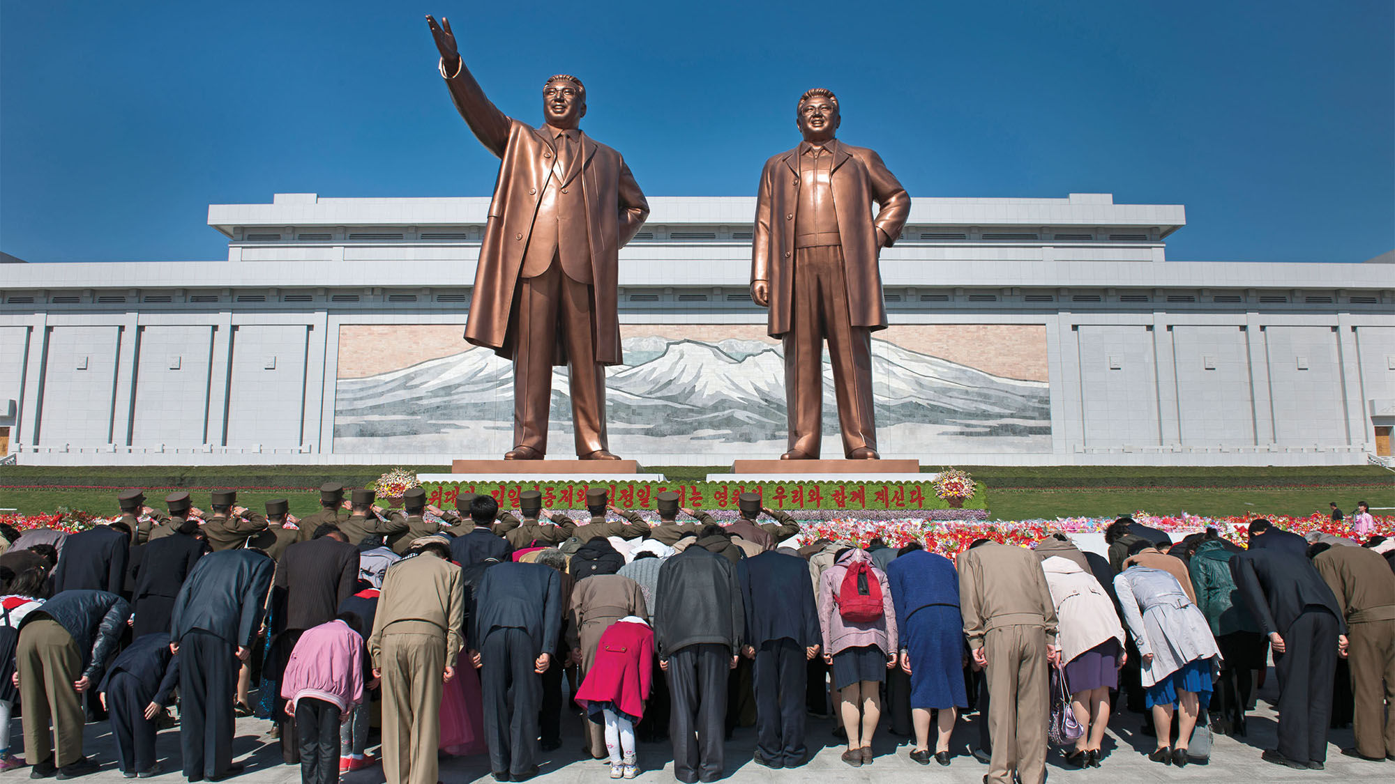 North Koreans bow to the newly unveiled statues of Kim Il Sung and Kim Jong Il in Pyongyang at the Mansudae Grand Monument.