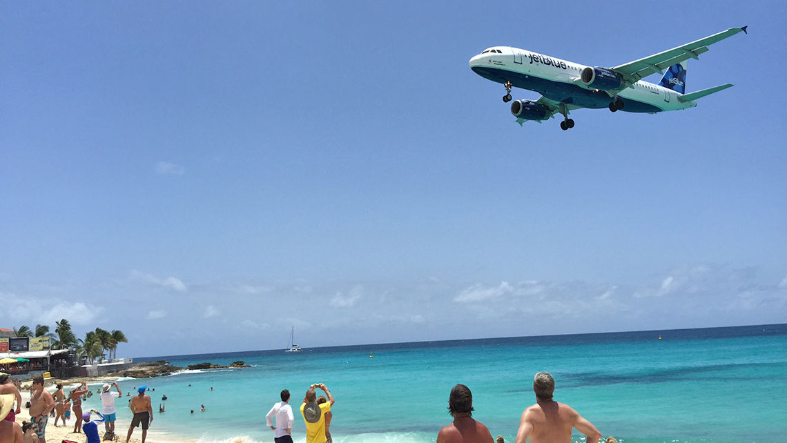 An airplane landing at Princess Juliana Airport comes in low over Maho Beach.