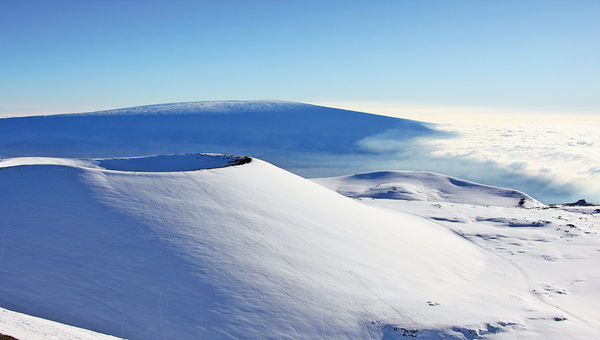 The snowy Mauna Kea summit on the Big Island. In the foreground is Mauna Loa.