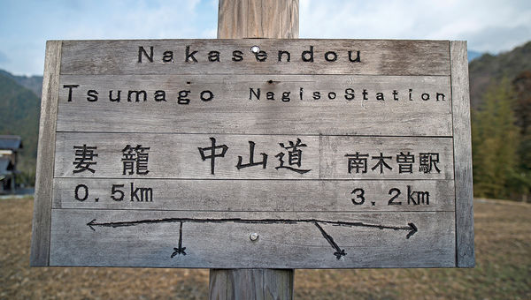 A rustic sign on the Nakasendo in English and Japanese points walkers toward Tsumago and Nagiso.