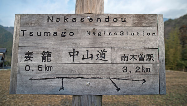 A rustic sign on the Nakasendo in English and Japanese points walkers toward Tsumago and Nagiso. A rustic sign on the Nakasendo in English and Japanese points walkers toward Tsumago and Nagiso.