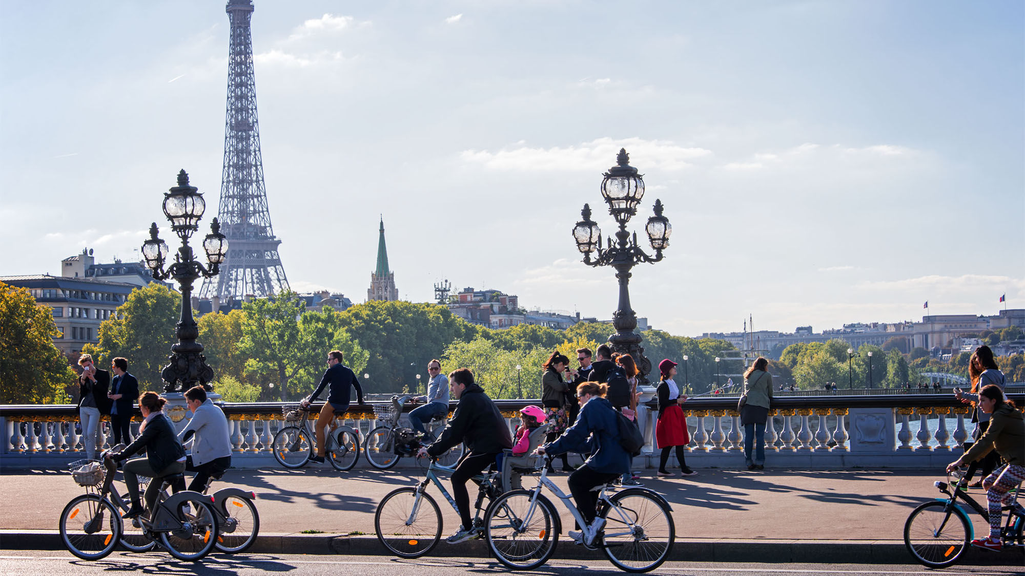 Pedestrians and bicyclists enjoying a car-free day on Alexandre III bridge in Paris.