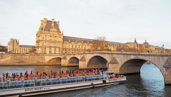 The week after the terror attacks in Paris: Tourists on a boat plying the Seine in front of the Louvre at sunset.