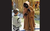 A young passenger dressed as a Stormtrooper approaches a Jawa at a Star Wars character meet-and-greet.