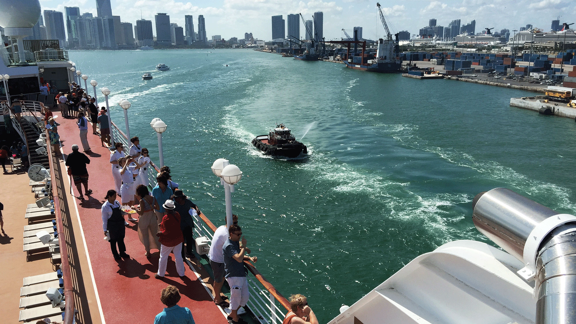 Passengers look on as a tugboat shoots a celebratory stream from a water cannon as the Adonia departs Miami for Havana.