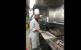 A chef slicing fish into fillets in the Empress of the Seas' galley.