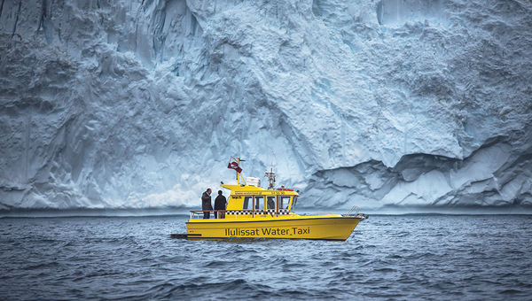 A water taxi sails in front of an iceberg near the Ilulissat Icefjord in Greenland. Sarah Woodall of Visit Greenland said some travelers are visiting to see the glaciers before they’re permanently altered.