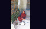 A woman cuts taro root on her porch between puffs from her pipe.