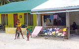 Laundry day: A father and his two children in front of their home after laying out their clothes on the island of Nadalla, as their mother watches from the shade of their porch.