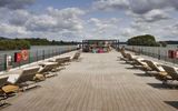 The upper deck features lounge chairs, shaded areas and outdoor furniture.