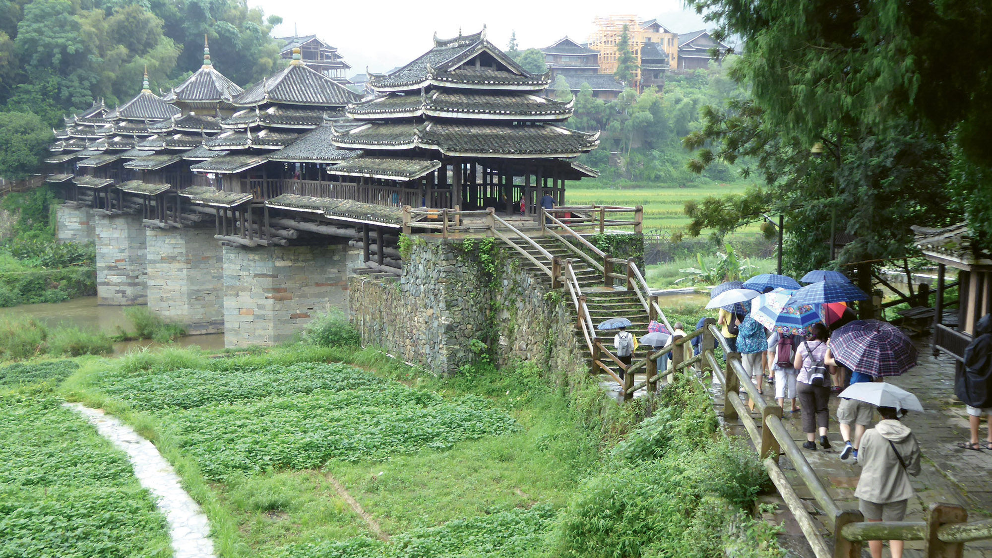 The ornate “Bridge of Wind and Rain” features thatched-roofed drum towers decorated with sculptures and frescoes.