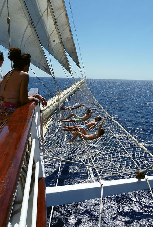 Star Clipper passengers lounge on the rigging beneath the bowsprit.